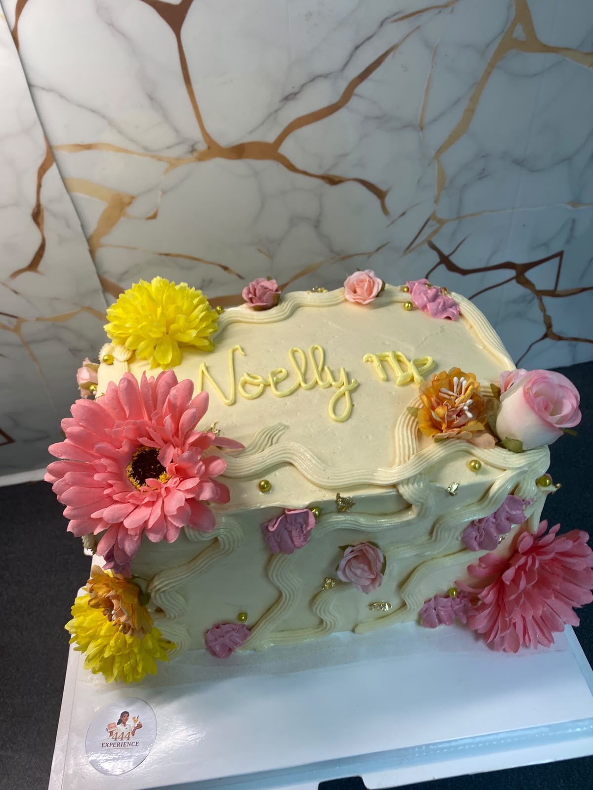 Gâteau crème orné de fleurs fraîches roses et jaunes